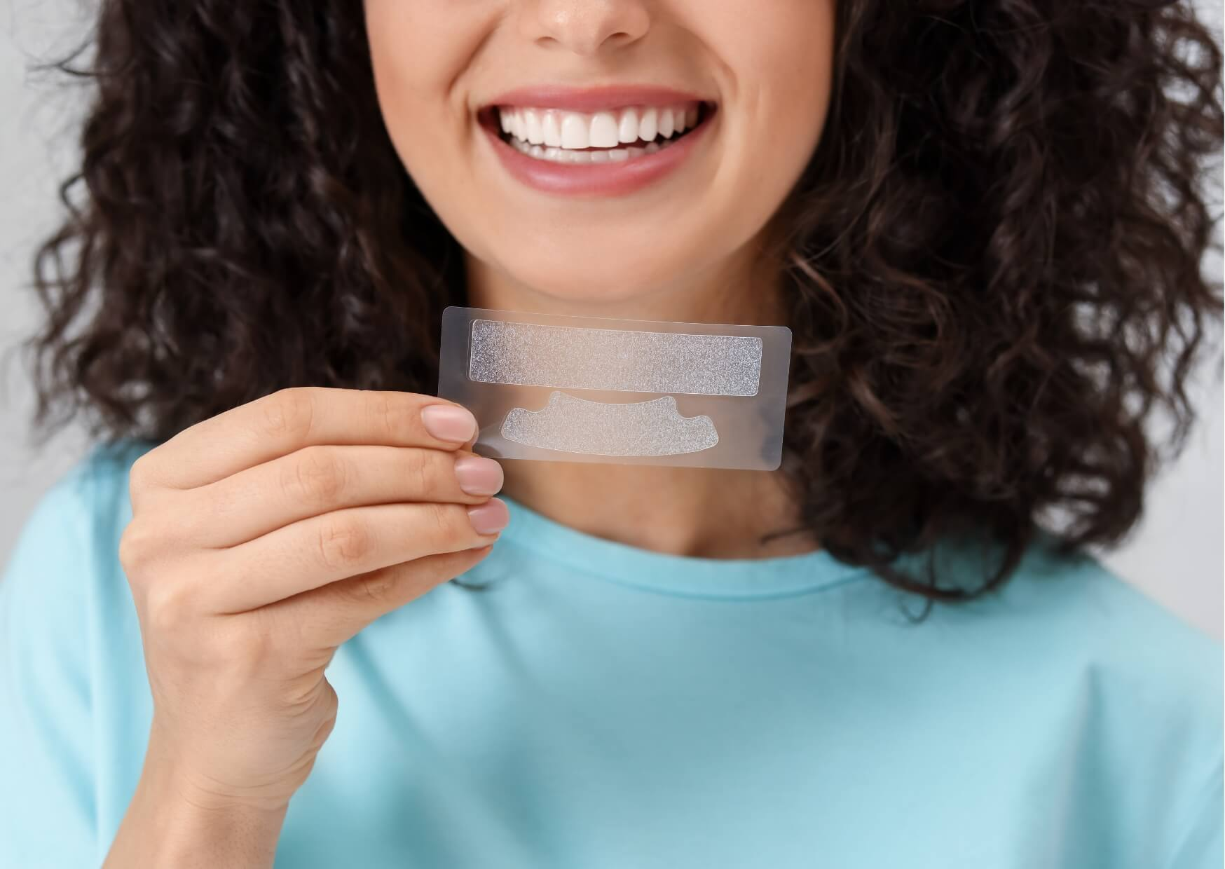 Person holding teeth whitening strips to illustrate how over-the-counter whitening strips can effectively brighten stained teeth when used as directed.