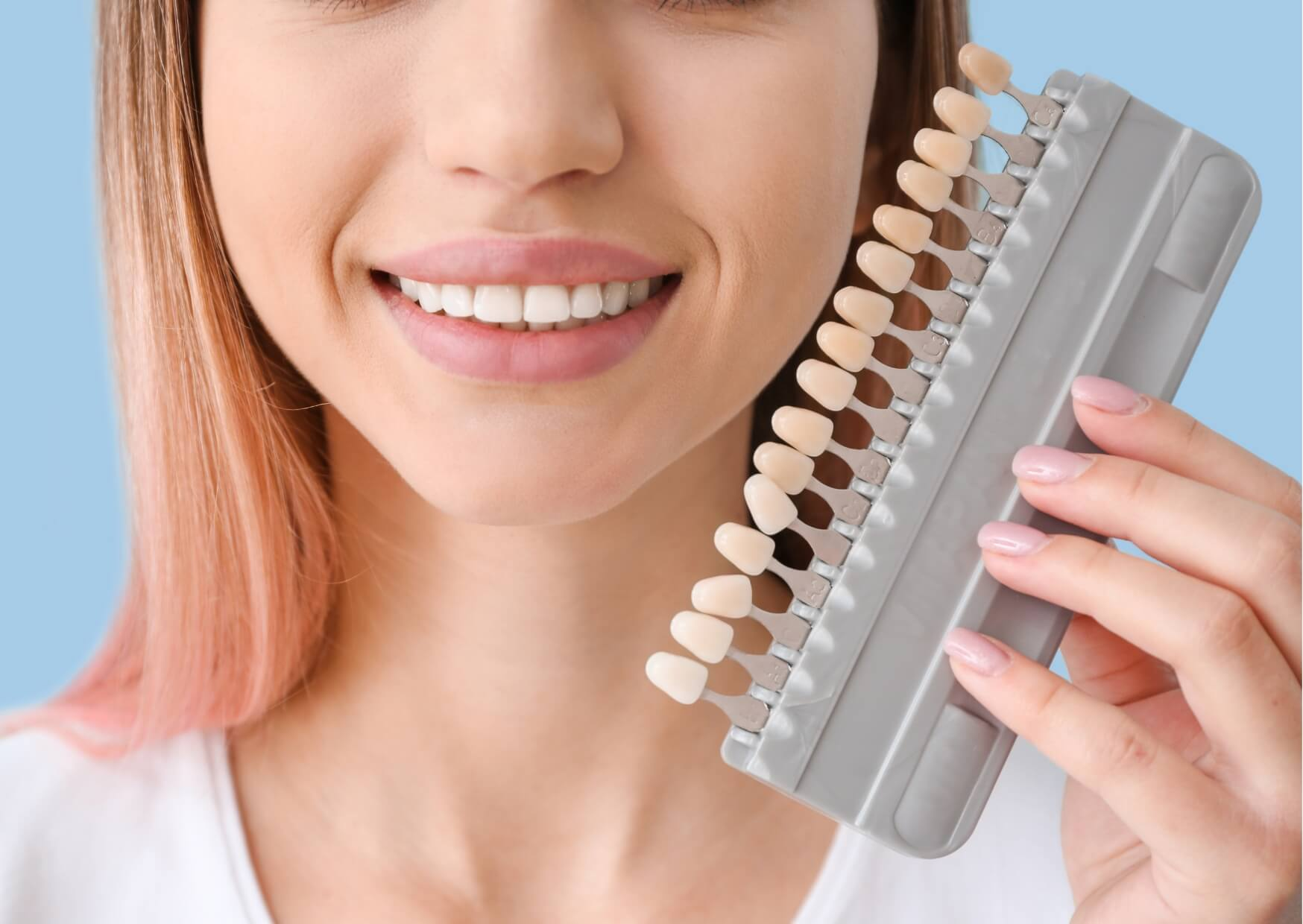 Patient holding a dental shade guide to compare veneer colors while learning about porcelain veneer costs and smile makeover options.