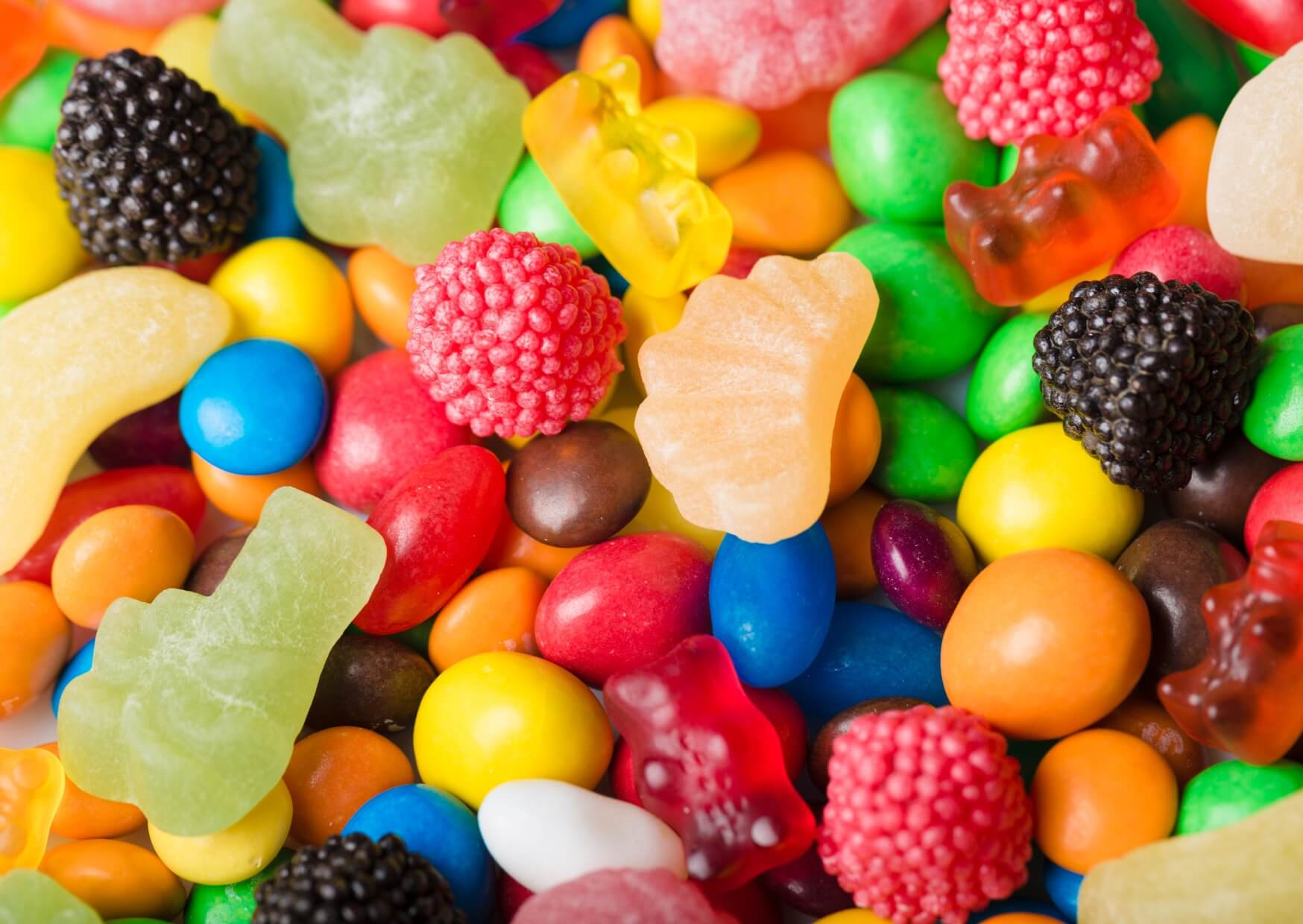 Colorful assortment of gummy candies and hard sweets that should be limited or avoided when eating candies with braces.