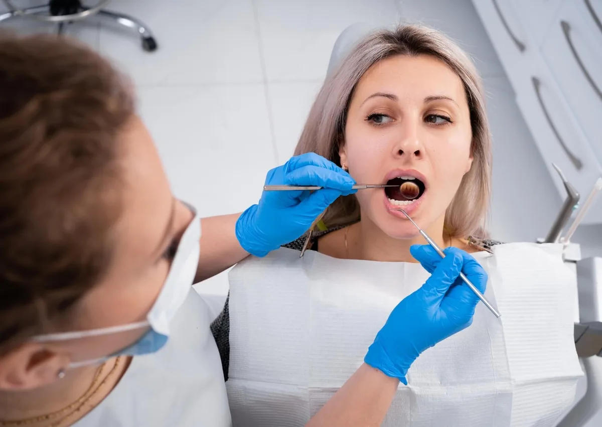 Dentist examining a patient’s mouth to evaluate a canker sore and its healing time.